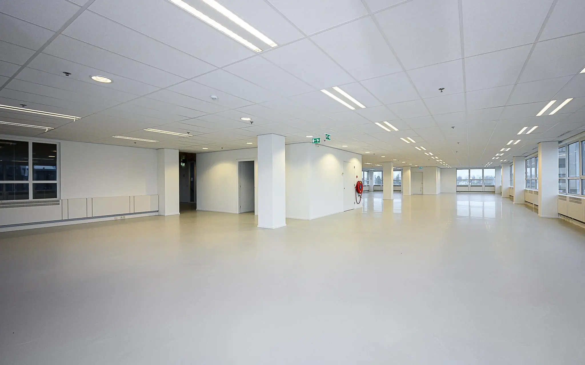 Leeg kantoorpand in Rivium Quadrant met witte muren, systeemplafond en grote ramen.